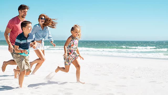 A family running on beach Happy family of four running on beach