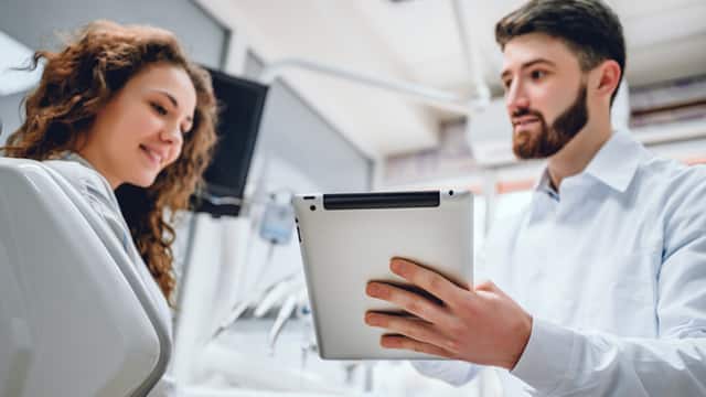 Male dentist discussing results on an iPad with female patient