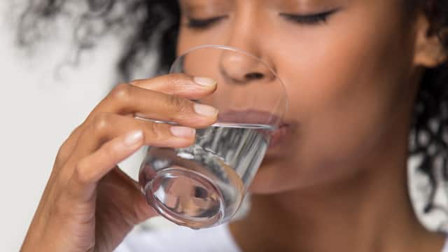 A woman is drinking water from the glass