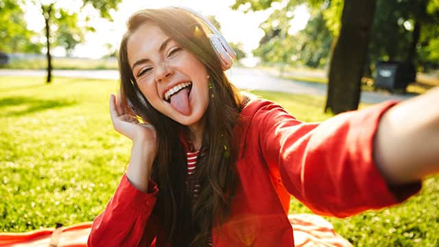 Mujer feliz sacando la lengua mientras escucha música