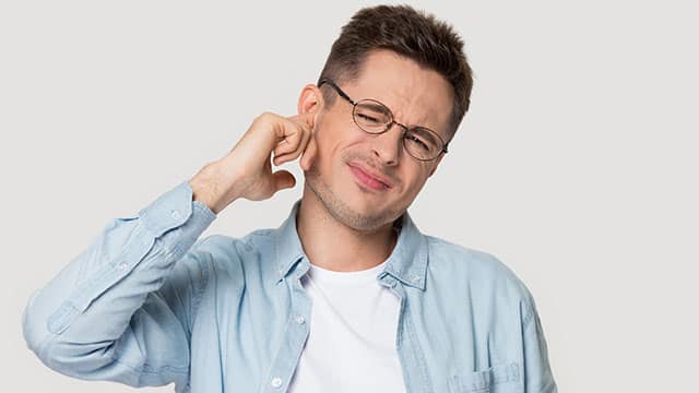 a young man with glasses who is suffering from an earache