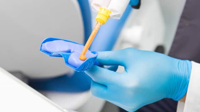A dentist is preparing a dental impression kit