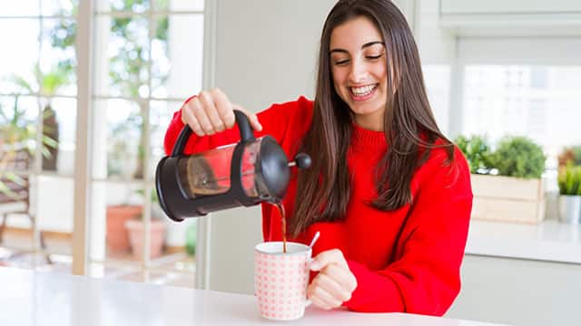 Young  woman making morning coffee and smiling