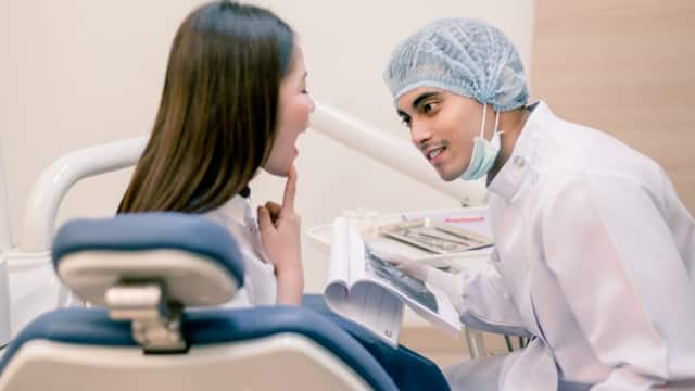 Male dentist examines female patient's teeth