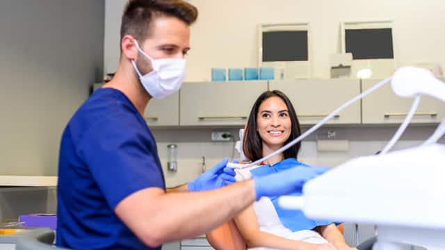 A male dentist preparing to work on a female patient