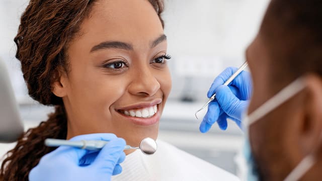 Woman smiling while being examined by dentist