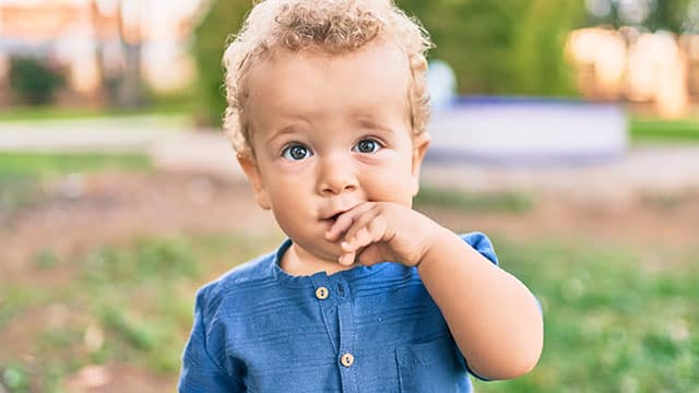 Little boy putting fingers on mouth