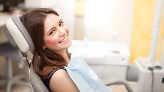 A woman confidently smiling in a dental chair
