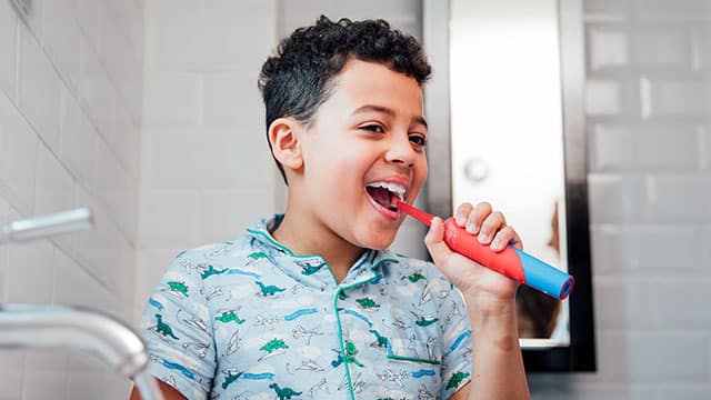 A boy is brushing his teeth with the electric brush