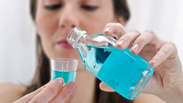 Close up of the woman's hand pouring mouthwash in to the cup