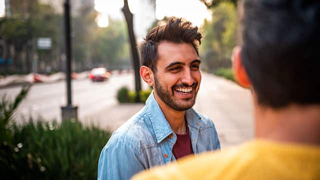 A man is smiling and talking to other man