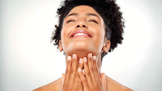 a woman smiling with her hands on her chin