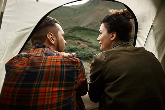 A couple camping in a tent outdoors