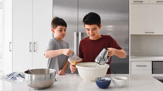Two boys mixing dough in a kitchen