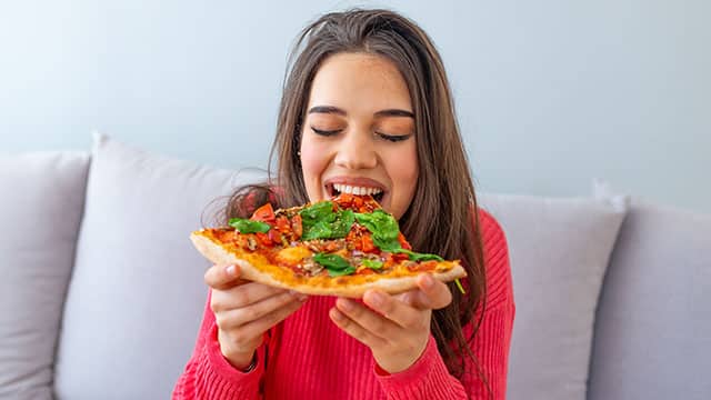 Young woman is eating pizza