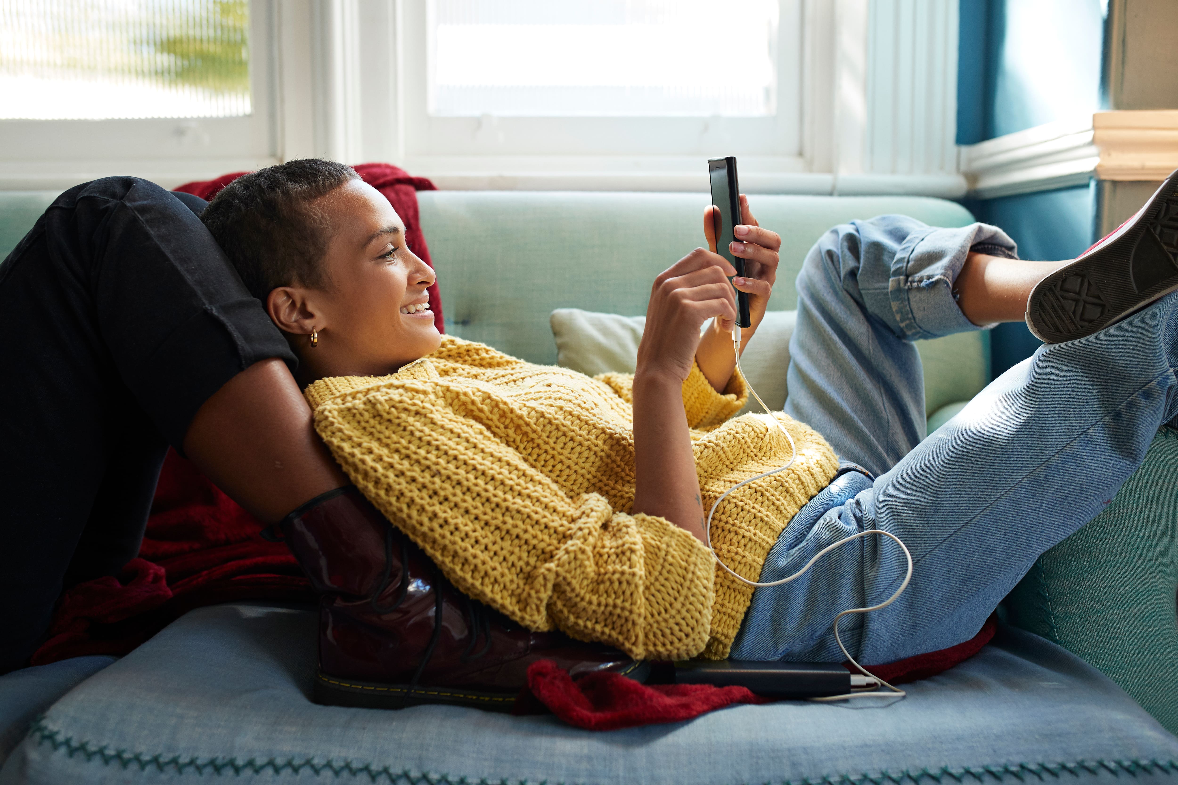 Woman laying on couch smiling at her phone