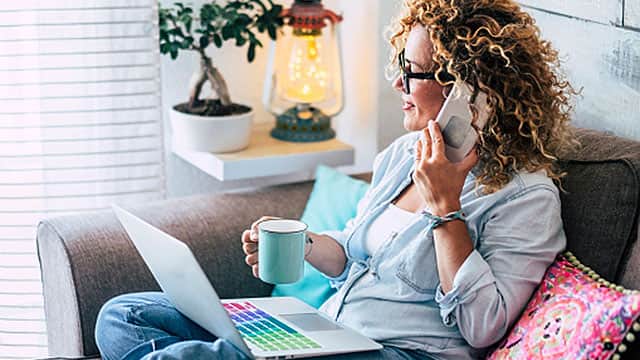 A woman is using a computer and talking on the phone inside A woman is using a computer and talking on the phone inside