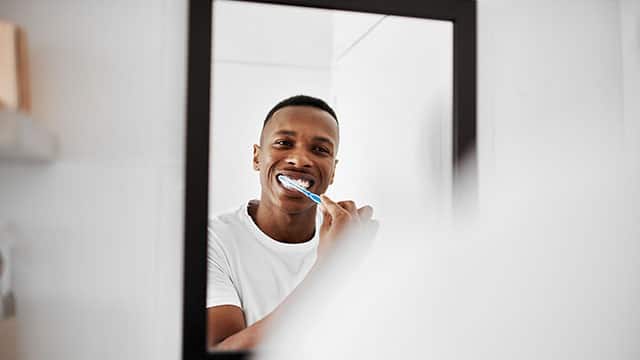 a man is brushing teeth in a bathroom 