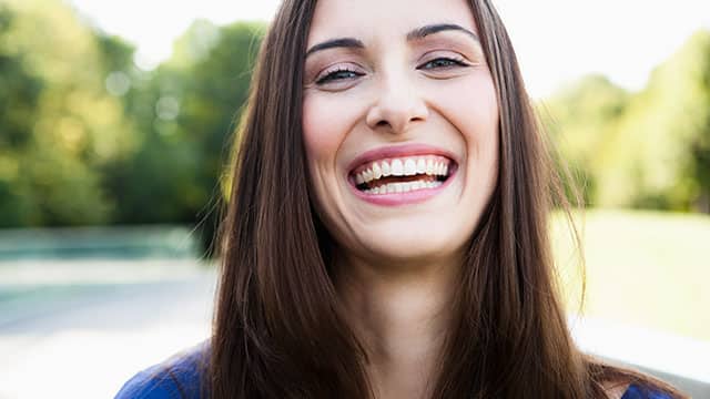 A young woman is laughing outdoors A young woman is laughing outdoors