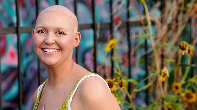 A bold woman smiling outside