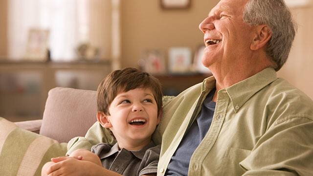 A grandpa and grand child on a couch laughing