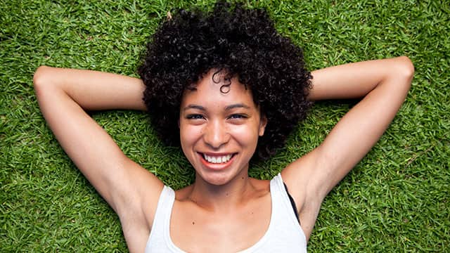 Young woman is lying on the grass smiling