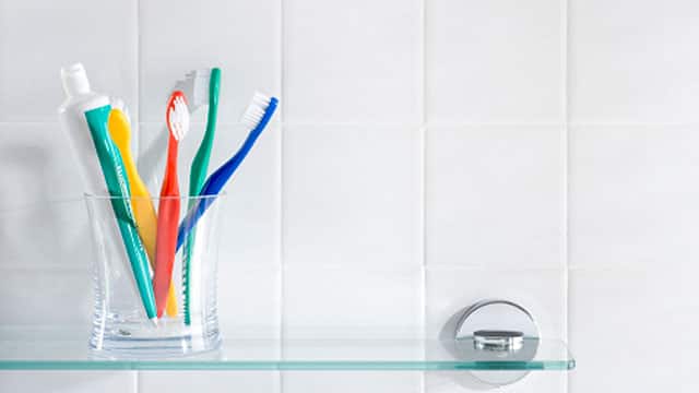Toothbrushes and toothpaste in a glass on a shelf