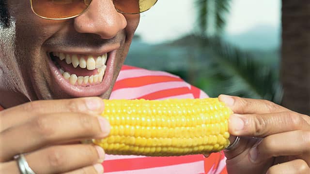 Close up of the man eating corn