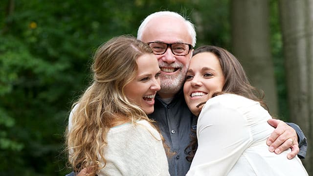 Smiling father hugging his two daughters