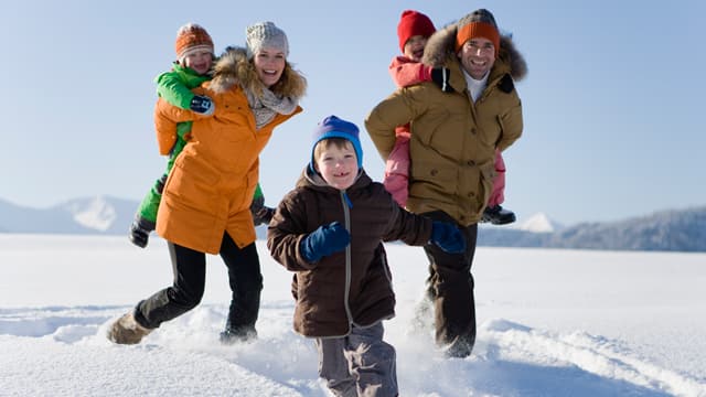 A family of five in cold weather clothes walking in the snow