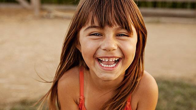 Young girl in red bathing suite smiling outdoors