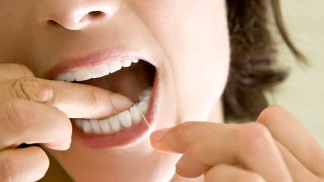 A woman flossing her teeth A close-up of a woman flossing her teeth