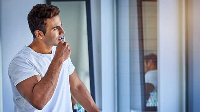 A man is brushing his teeth in a bathroom