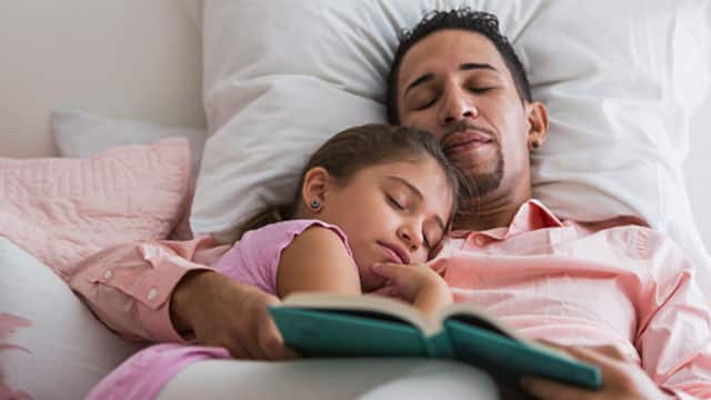 Papá e hija durmiendo después de leer un cuento