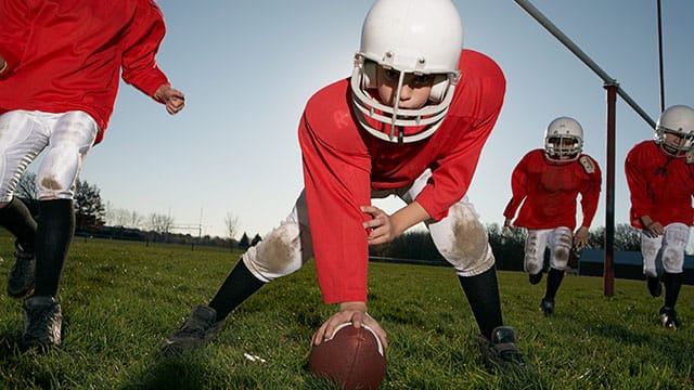 Kids playing football in full safety gear 