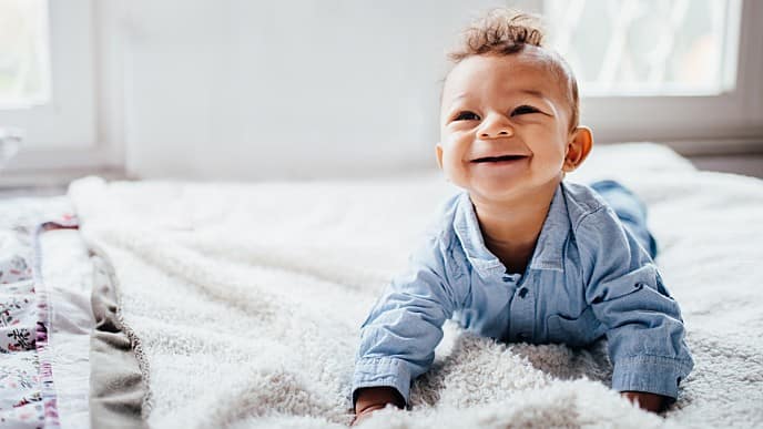 A happy little baby crawling on bed