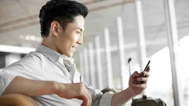 A man looking smiling while looking at his phone