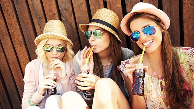 A group of girl friends drinking soda on the pier