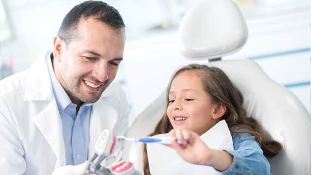 girl at the dentist learning to brush her teeth properly