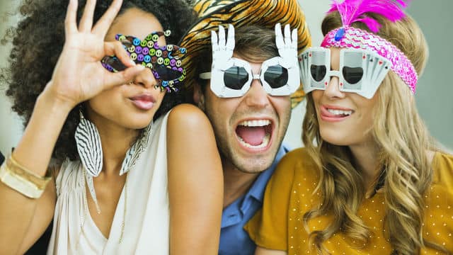 three friends laughing while wearing funny glasses