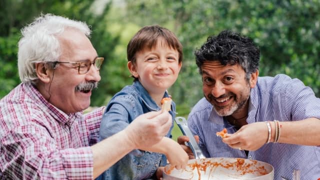 a grandfather, father and young son are enjoying a meal together