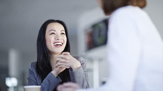 a woman smiling brightly while conversing with the dentist