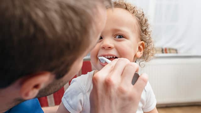 father brushing his son's teeth
