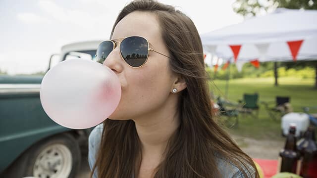 a girl is blowing gum bubble after knowing how to avoid dental caries