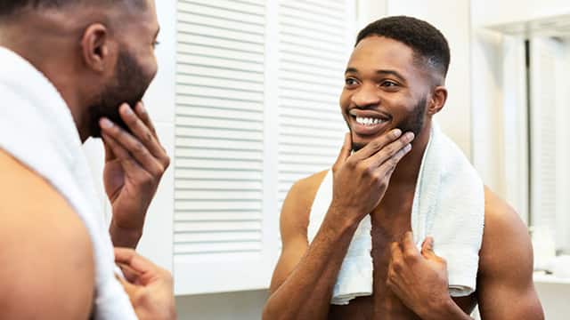Cheerful guy looking at mirror enjoying the reflection of his smile in the bathroom