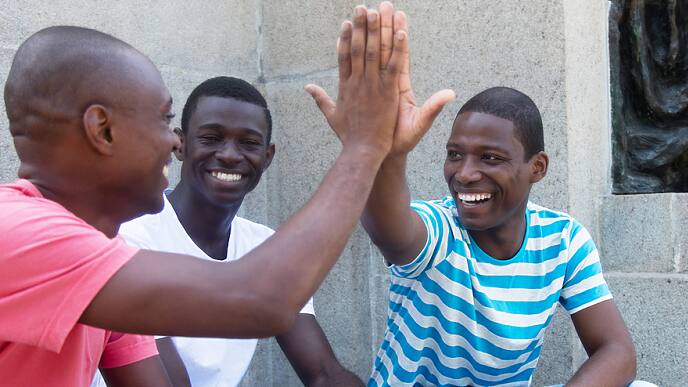three man smiling brightly and high-fiving each other