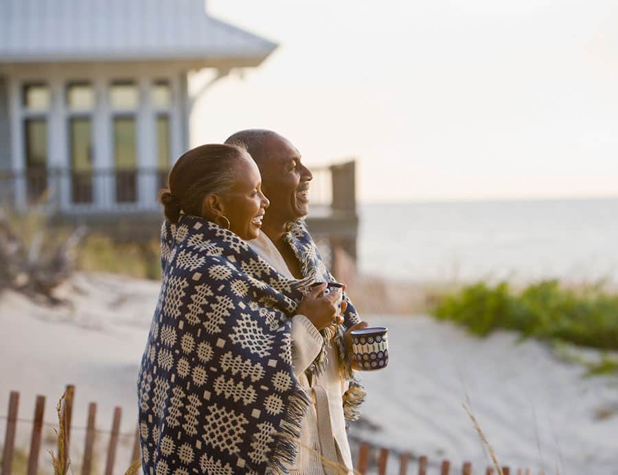 Senior couple wrapped in blanket on the beach