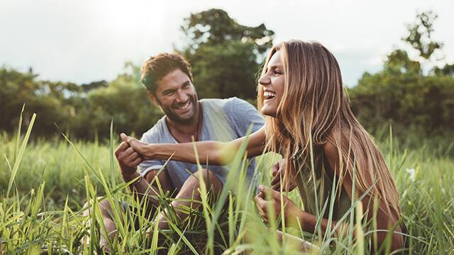 couple laughing in a field on a sunny day