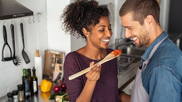 Couple smiling while tasting food in a kitchen