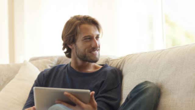 man smiling while holding a tablet